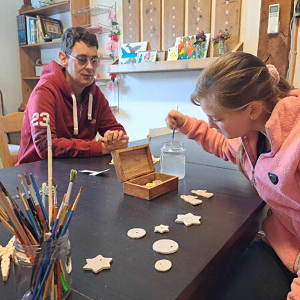 Een man en een meisje werken samen aan een project, met materialen en notities verspreid op een tafel.