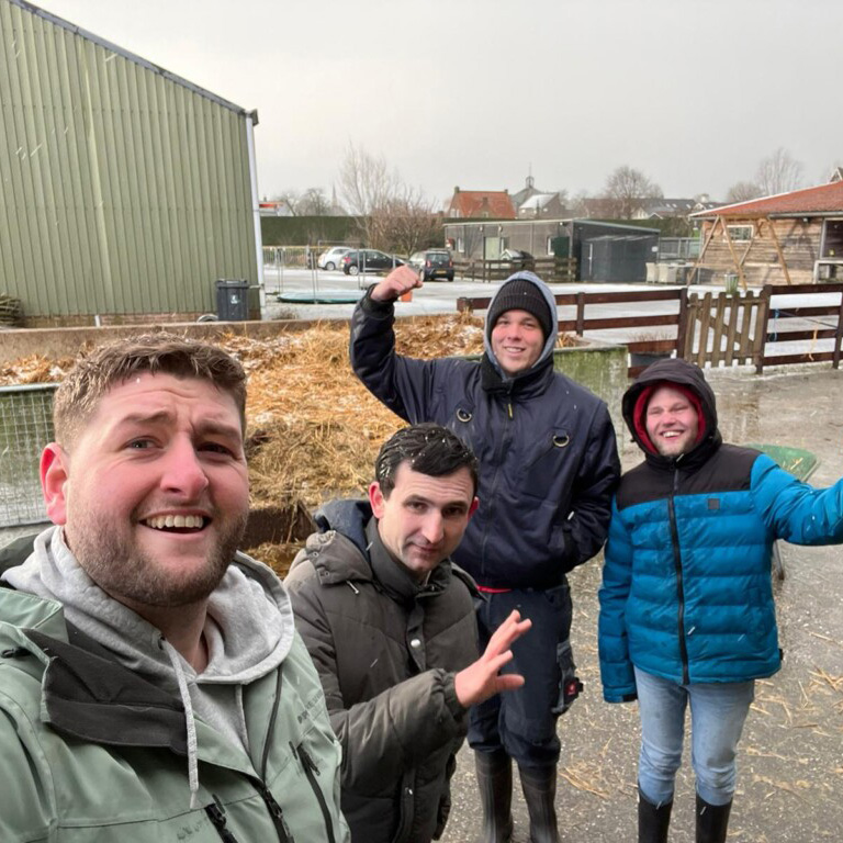 Vier mensen poseren voor een schuur voor een groepsfoto.